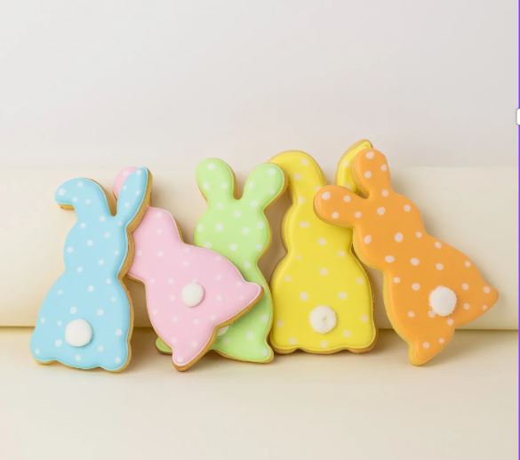 A photo of some biscuits in the shape of bunny rabbits. They are decorated with coloured icing.