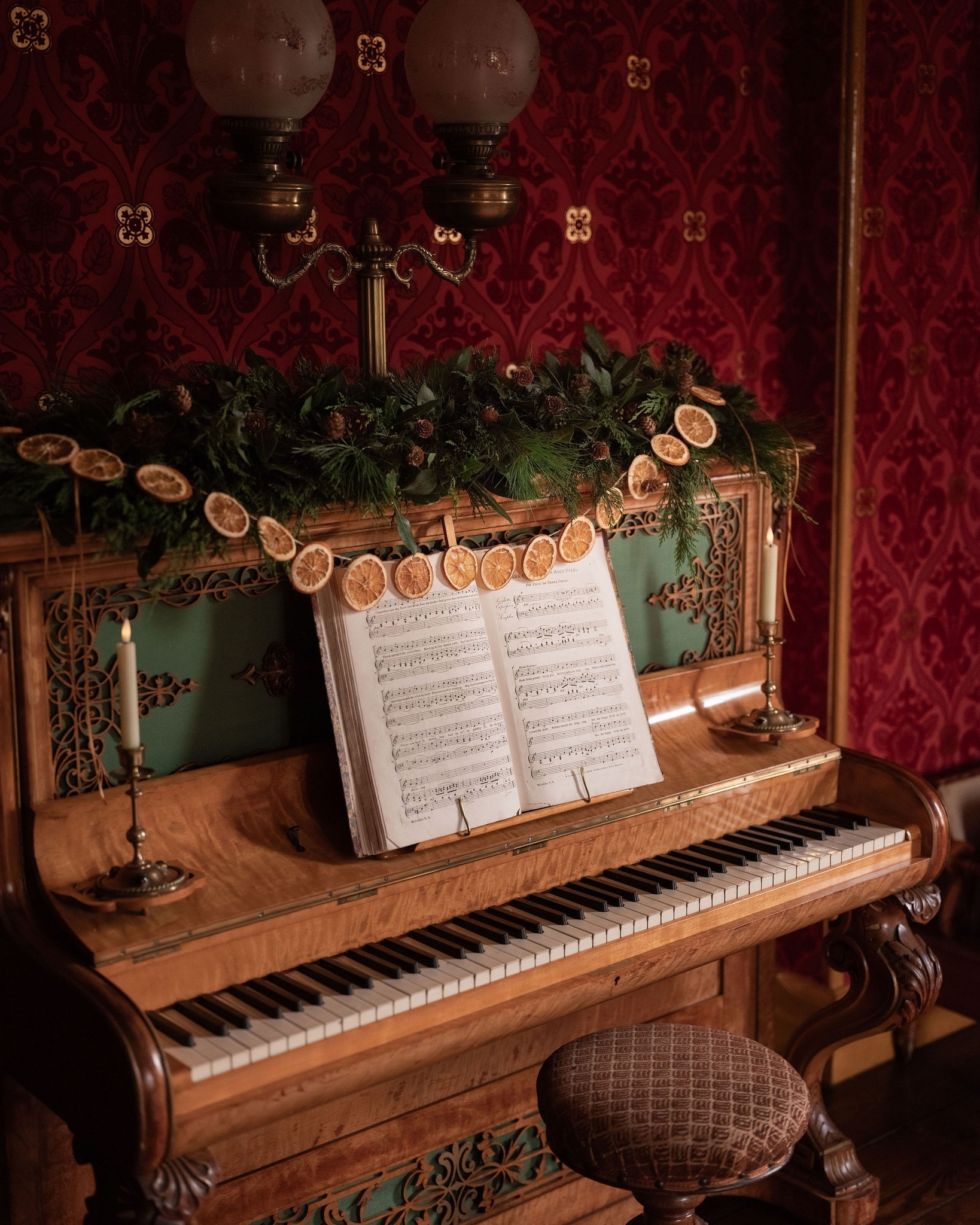 The piano at Story of Emily decorated for Christmas with traditional foliage and a garland of dried orange slices