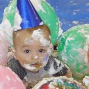 photo of a baby surrounded by balloons and white messy foam