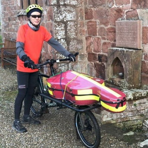 A photograph of Kenneth Wilson with his bike that has been specially designed to hold his cello.