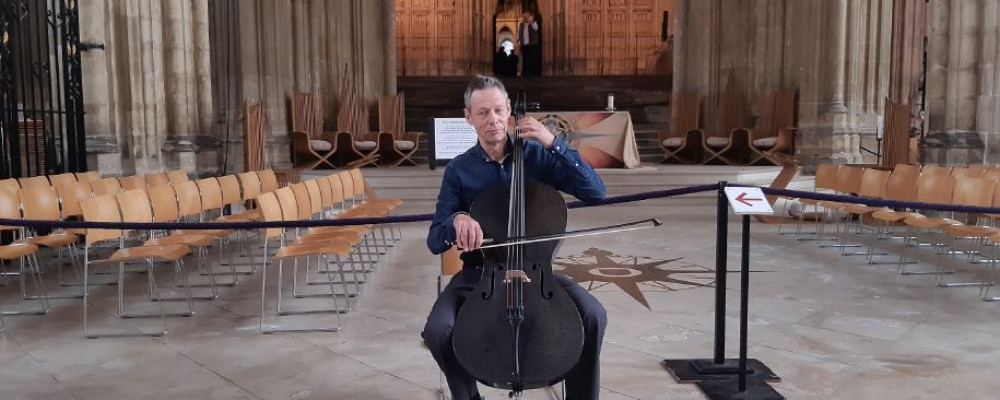 A photograph of Kenneth Wilson playing his cello in a church