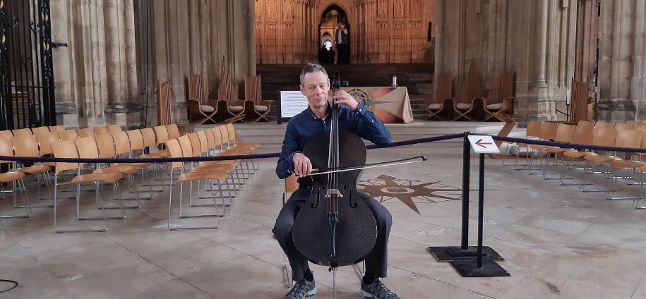 A photograph of Kenneth Wilson playing his cello in a church