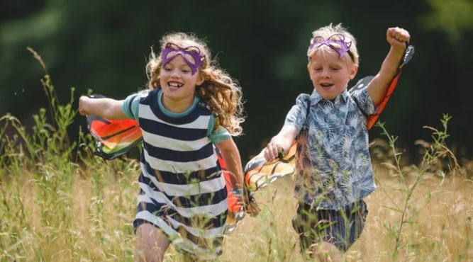 A photograph of a boy and a girl running in a field.