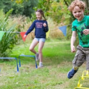 A photograph of two children a girl and a boy playing in a garden. 